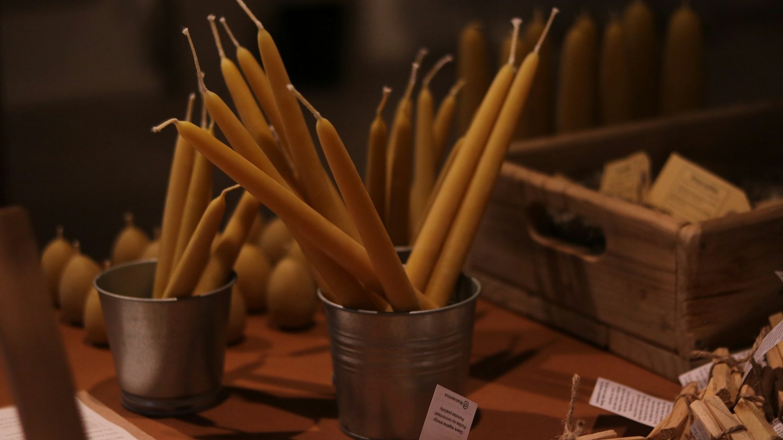 Tall yellow candles standing upright in metal holders on a table